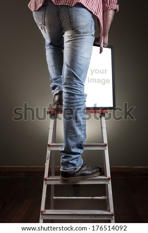 Man holding picture frame while climbing on ladder