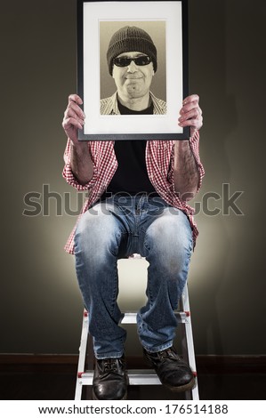 Man holding picture frame while sitting on a ladder