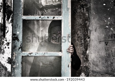 Man behind dirty glass in a spooky dark room