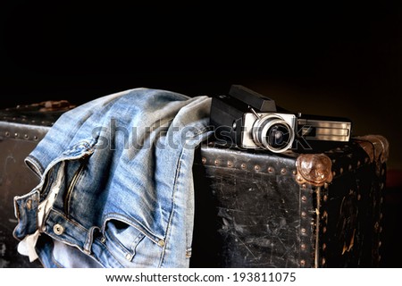 Pair of jeans and old movie camera on a vintage suitcase