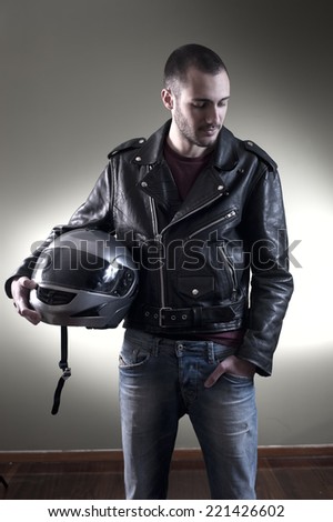 Biker in leather jacket posing holding his helmet
