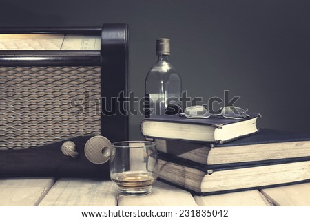 Composition with vintage items on table Vintage radio, books, glasses and whiskey on wooden surface. Edited image with vintage effect