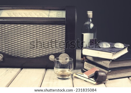 Composition with vintage items on table Vintage radio, books, glasses tobacco pipe and whiskey on wooden surface. Edited image with vintage effect