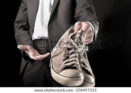 Businessman holding dirty sneakers