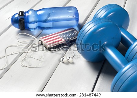 Dumbbells, plastic bottle of water and smart phone with headphones on floor