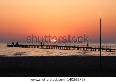 An old sea pier on the background of the setting sun (Russia, the Black Sea).