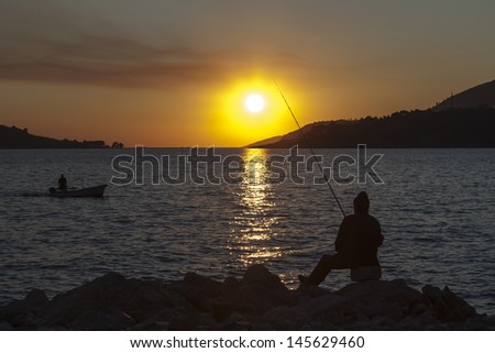 Montenegro, Budva town. Evening fishing on the backdrop of the setting sun.