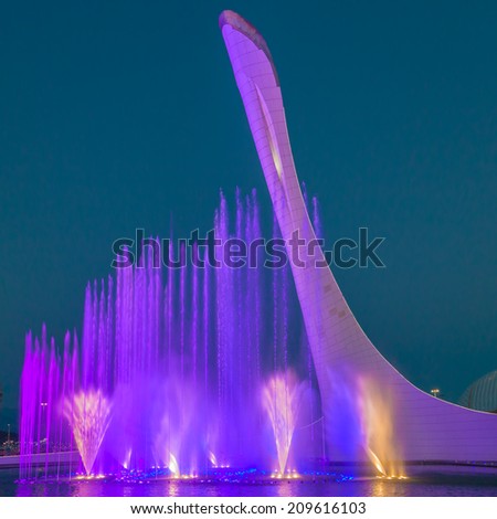 Sochi Olympic Park. Light and music fountain on the background of the Olympic torch in the summer evening.
