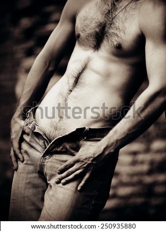 Naked sexual brawny male torso. The man in jeans with a naked torso.