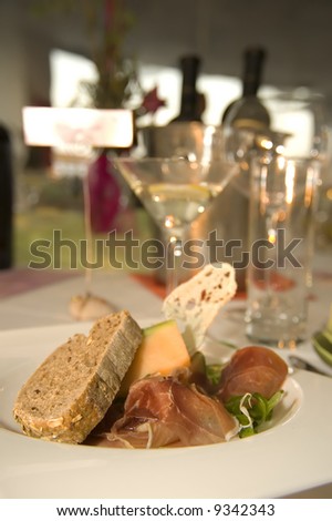 Wedding reception table with plates, meals and bottles of wine.