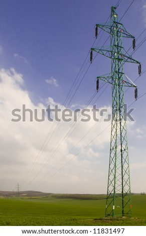 Many electricity pylons with wire in the green fields
