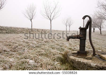 Old rusty water pump on the countryside in freezing winter
