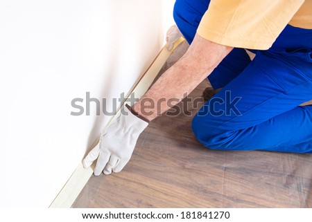 Worker covering the floor of the room to protect it during painting