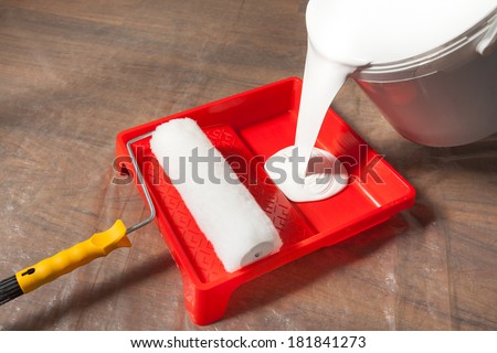 Preparing for painting, pouring paint from bucket into a paint tray.