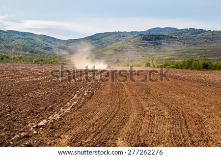 A tractor is cultivating the soil before sowing in the early spring. The machine perform this activity to loosens the soil after the deep plowing and before the new seeds to be sown.