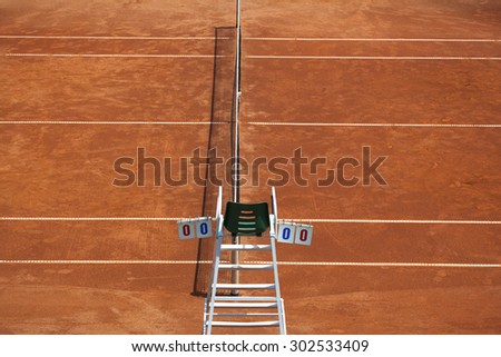 Umpire chair with scoreboard on a tennis court before the game. The playground is empty and the score is zero to zero.