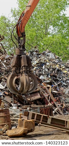 inustrial machine with scrap metal grapple in front of scrap iron