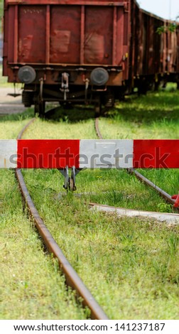 red white barrier to the railroad tracks with wagon