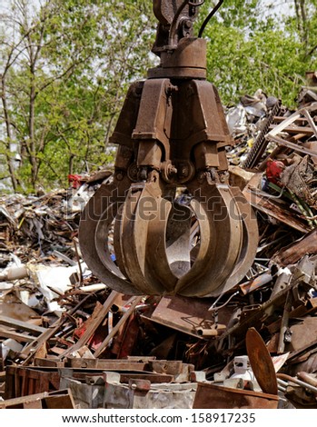 inustrial machine with scrap metal grapple in front of scrap iron