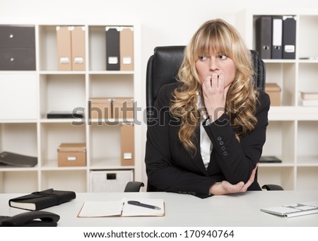 Pensive worried businesswoman biting her nails and looking off to the side with a serious thoughtful expression as she anticipates trouble