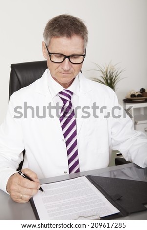 Male Medical Doctor Signing Medical Document on Table