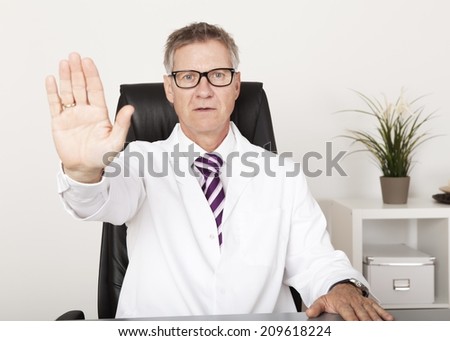 Serious Doctor Showing Hand Stop Sign While Sitting on Chair