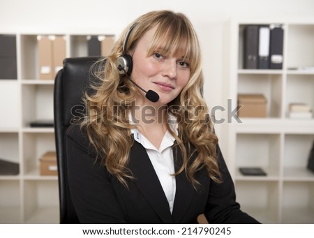 Friendly businesswoman wearing a headset looking at the camera with a lovely smile conceptual of a call center, client services, reception or telemarketing