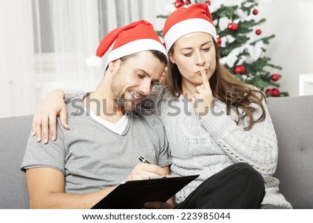 happy young couple think about to do list for christmas eve on sofa