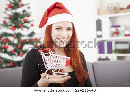 young happy christmas girl showing mini shopping trolley cart, for presents or gifts