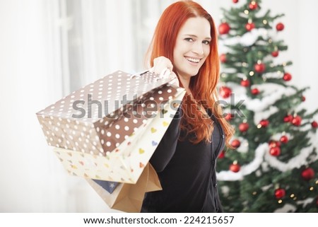 young happy red haired girl with a lot of christmas bags is surprised and feel good with shopping present gift boxes