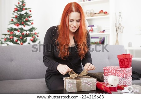 young happy girl wrap christmas present boxes for family with tree in the background