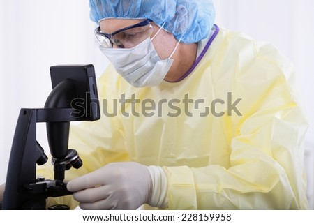 portrait of scientist or doctor in protective gear working with microscope and blood, in lab or hospital