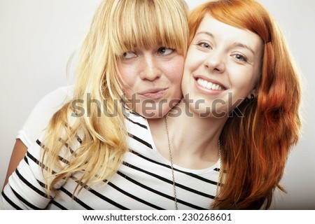 red and blond haired girls friends laughing and hug