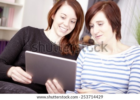 portrait of  two happy young girls with tablet computer at home