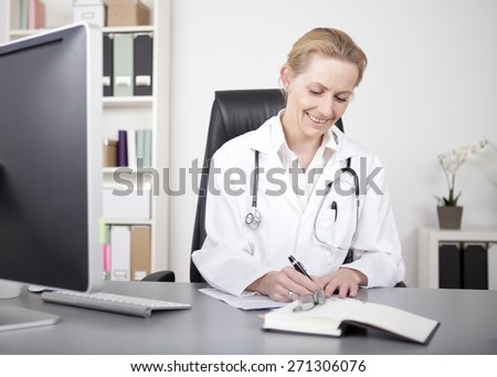 Happy Adult Female Doctor in White Gown with Stethoscope Sitting at her Office While Writing Some Medical Reports for her Patients.