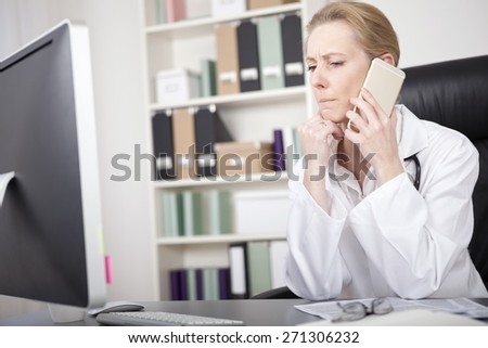 Close up Serious Adult Woman Doctor Sitting at her Office While Listening to Someone Over the Phone and Leaning on her One Hand