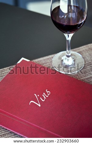 Wine list and glass of red wine in a French restaurant