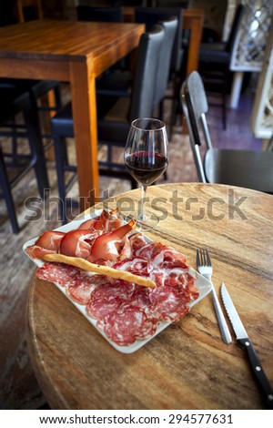 Ham, bacon and sausage on a plate, glass of red wine