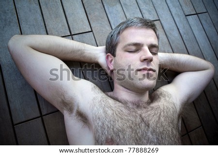 Hairy young man asleep on a wooden deck