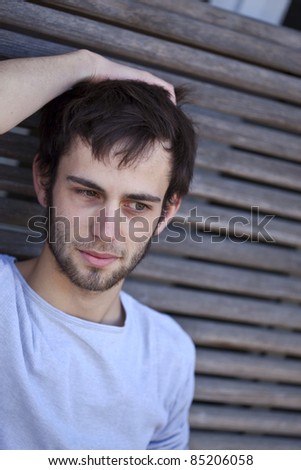 Young man sitting on a bench, trying to think