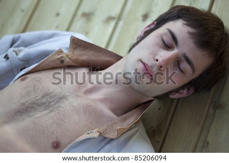 Shirtless young man with a jacket, sleeping on a wooden deck