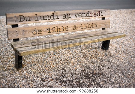 Opening hours of a park engraved on a wooden bench