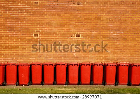 The line of recycle bins next to a brick wall