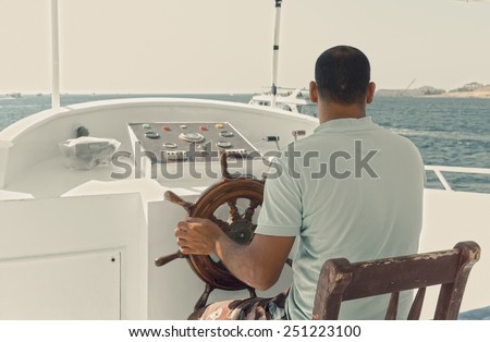 Vintage tinted photo of captain of a yacht sitting by the steering wheel