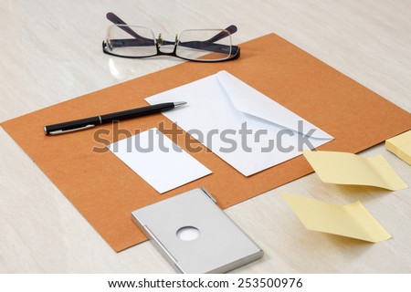 A set of blank envelopes with paper, pen, glasses, business card ans sticky notes side view