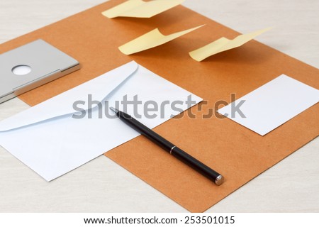 A set of blank envelopes, sticky notes, business card and pen side view