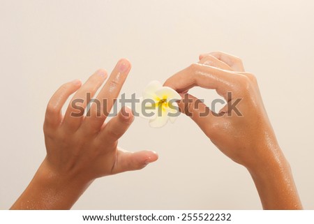 Golden tinted photo of female hands in oil holding magnolia flower on beige background view 6
