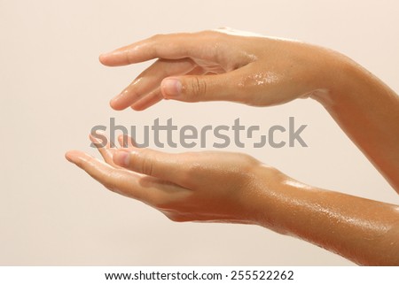 Golden tinted photo of female hands in oil on beige background view 1