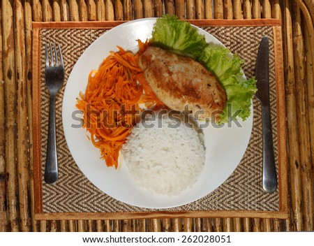 Chicken escalope with steamed rice and carrot salad on white plate top view 2