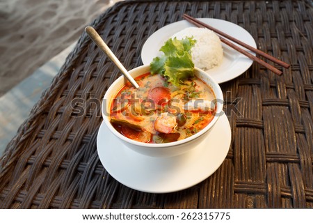 Natural light photo of Tom Yam seafood soup served with rice, shallow DOF seaside view 2